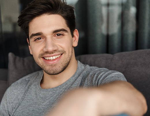 man smiling while sitting on couch 