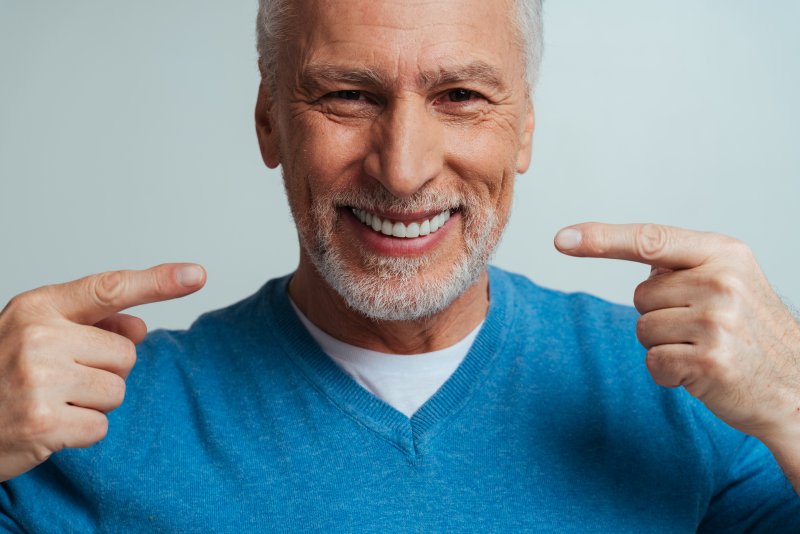 a man smiling and pointing at his dentures